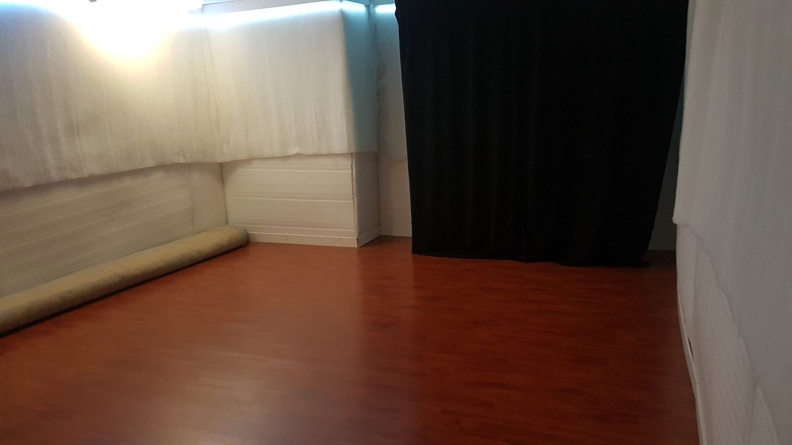 A second view of the completed CLOUD Studio showing the wood floor, padded walls, curtain, and open movement area.