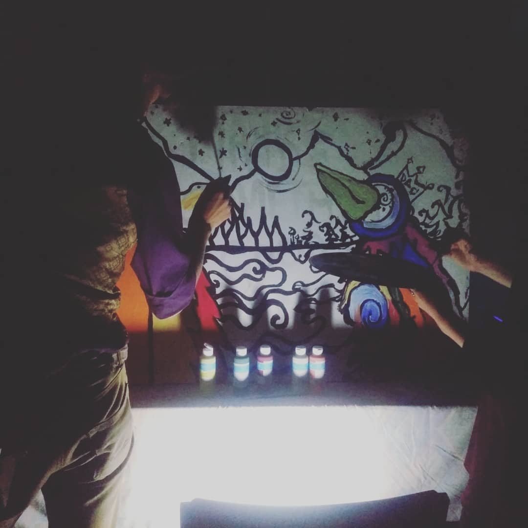 Participants manipulate shadow imagery around an illuminated overhead projection surface during Shadowjam.