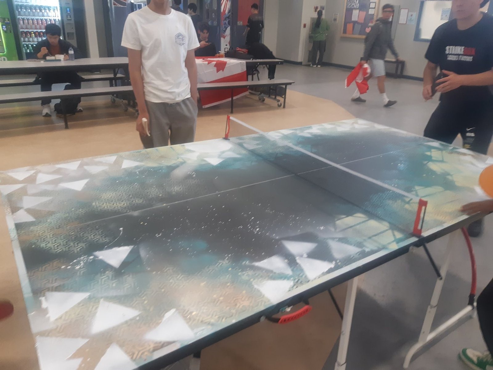 Students gather around the Sonic Ping-Pong table during a live activation in a school common area.