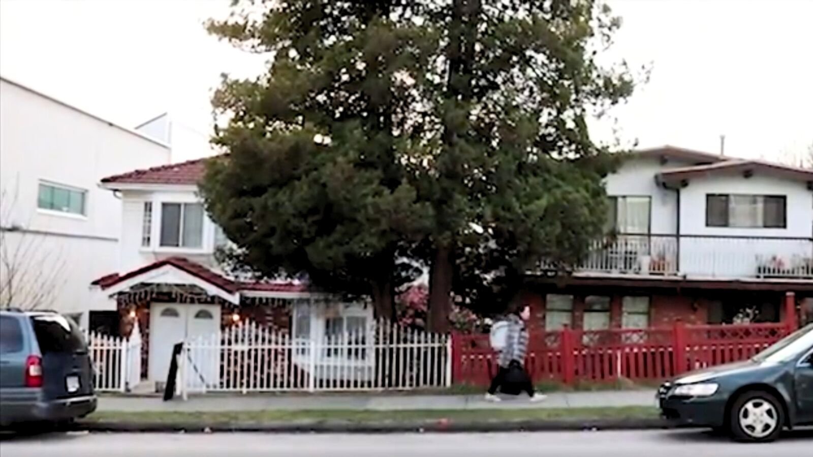 Street view of the Wheel of Time Gallery house behind a white fence and large tree