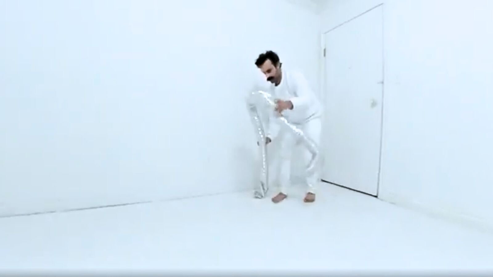 Raj Gill performing with a reflective sculptural form inside the white room