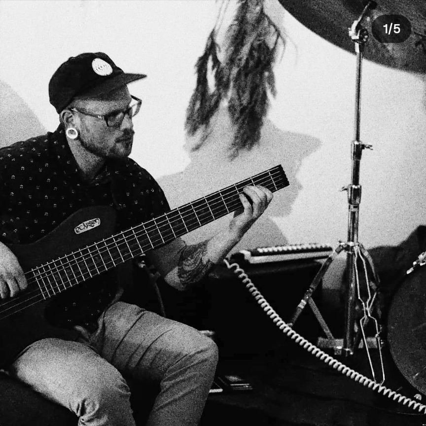 A musician playing bass guitar in a small room